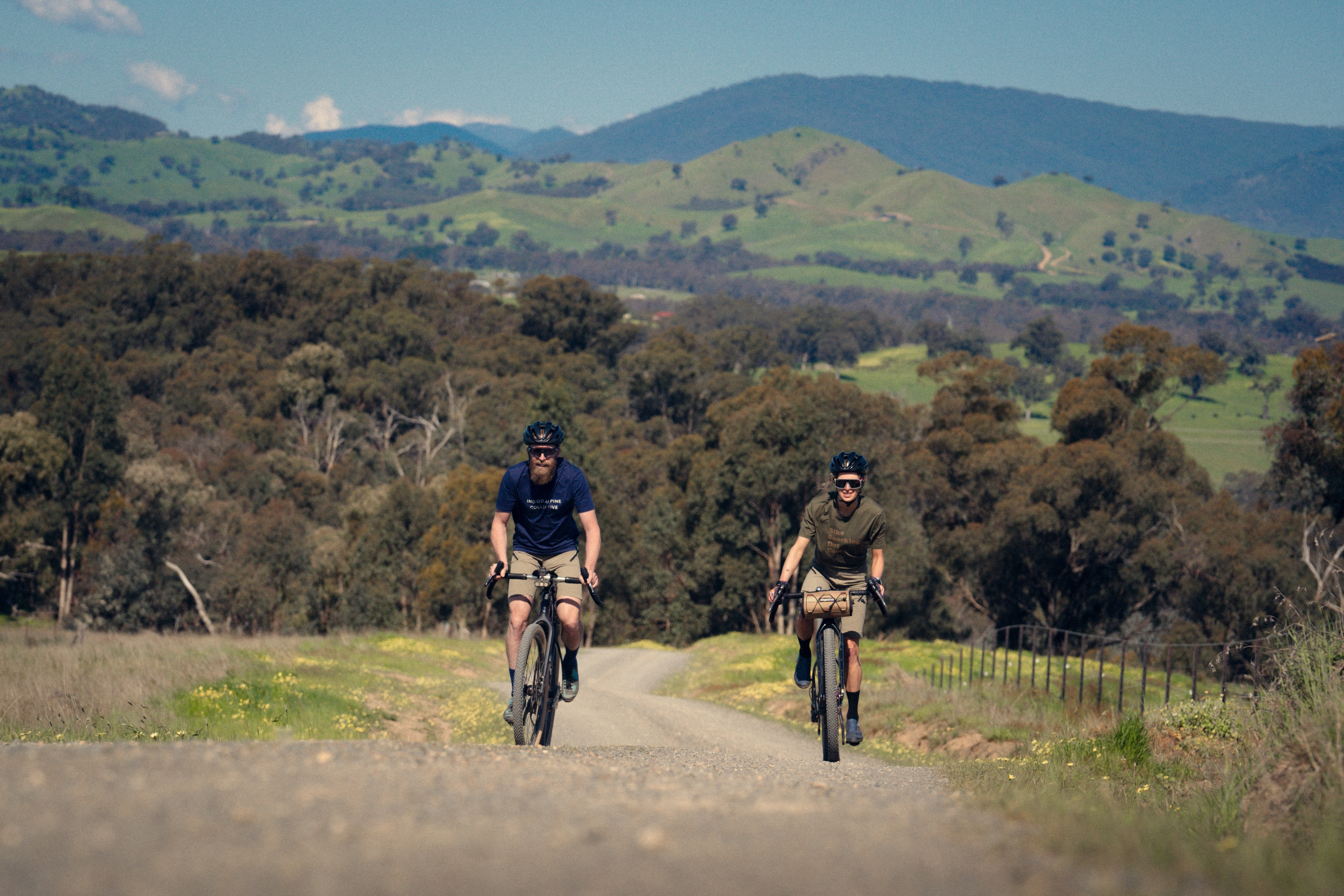 Two cyclists riding the gravel route of Goin to Bonnie Doon past hills and farmland.